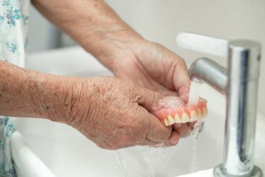 Asian senior woman patient wash and clean denture in nursing hospital.